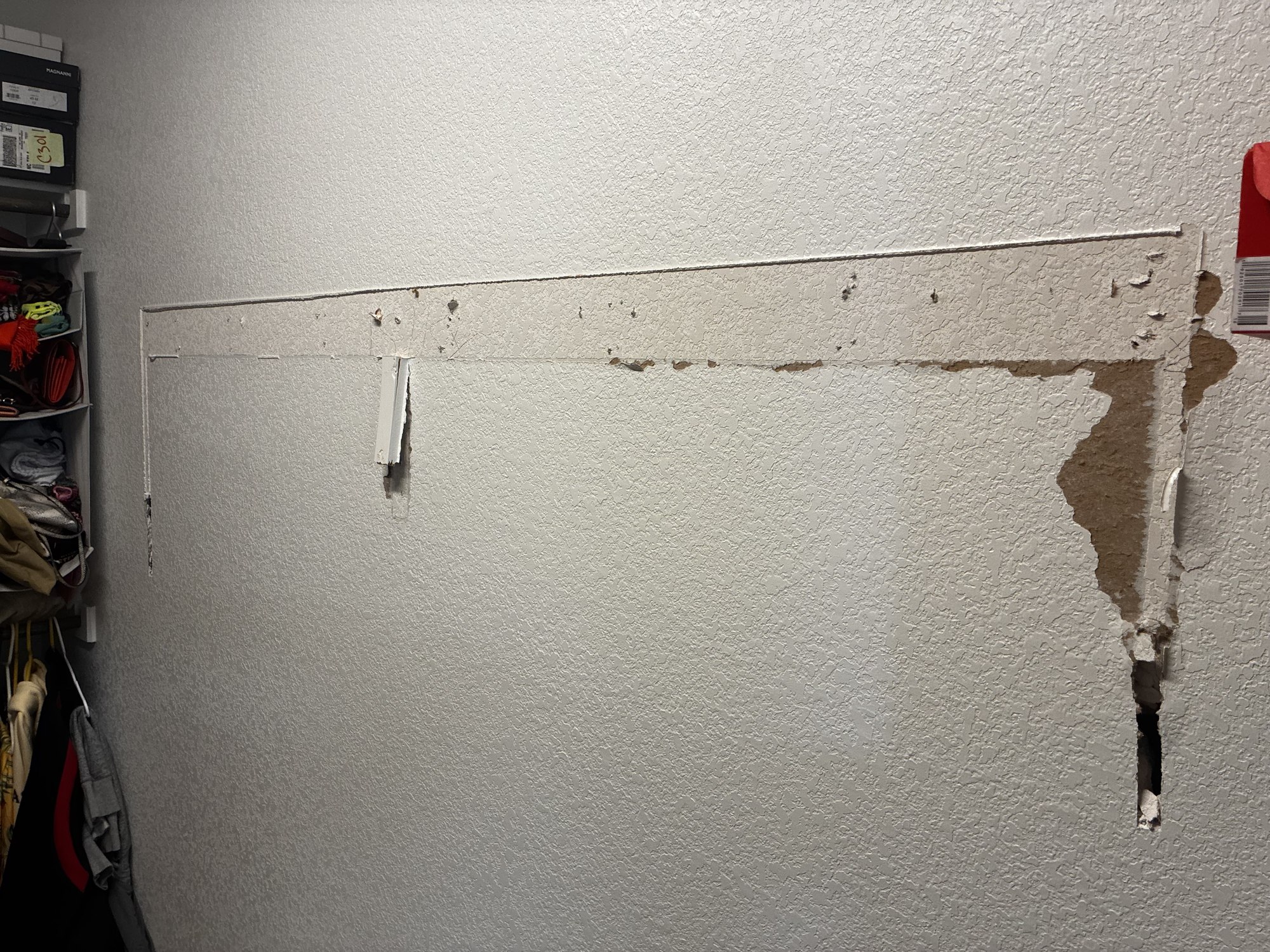 Closet wall with torn drywall paper and mounting holes where a shelf was removed.