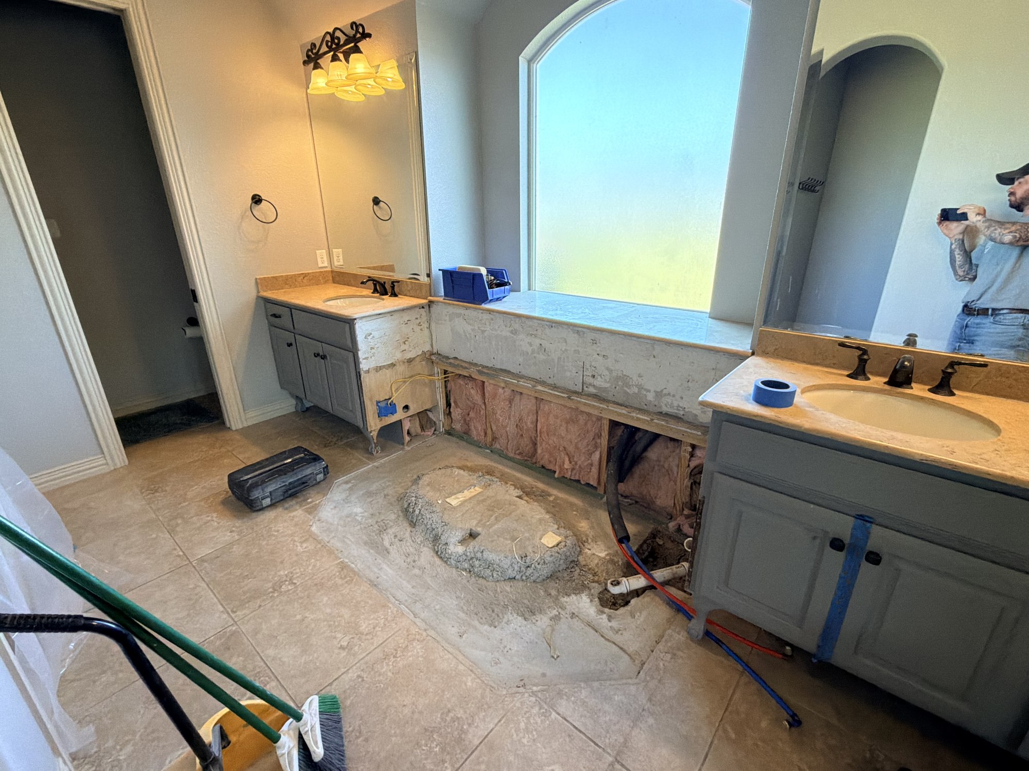 Bathroom renovation with exposed wall framing, insulation and plumbing between two vanities.