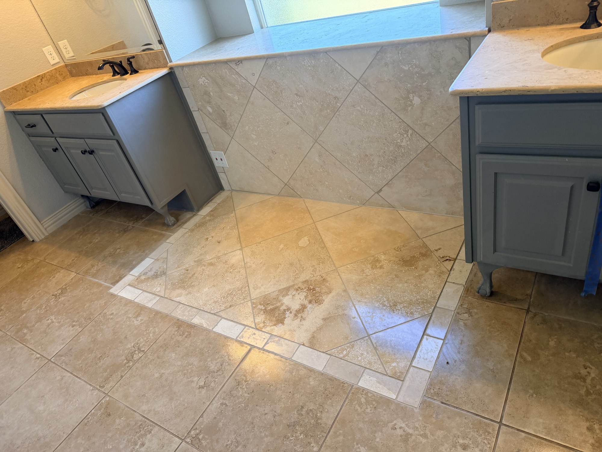 Close view of diagonal bathroom floor and wall tiles between two gray vanities.